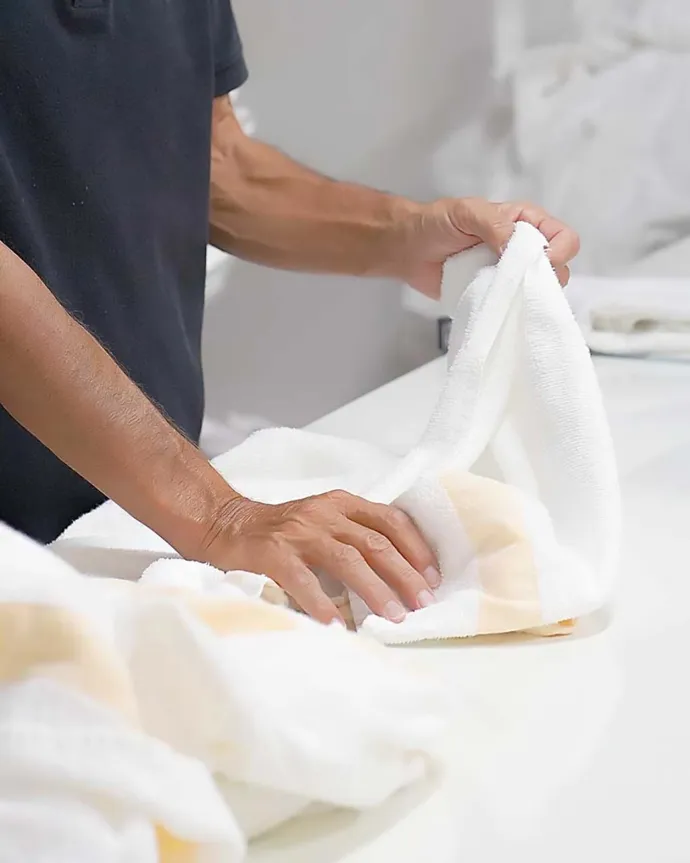 Person folding towels in a laundry room.